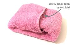 a pink towel that is folded up and labeled with the words safety pin hidden by top fold