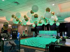 a room filled with lots of green and white balloons hanging from the ceiling above it