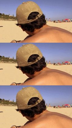 the back of a man's head wearing a baseball cap on top of a sandy beach