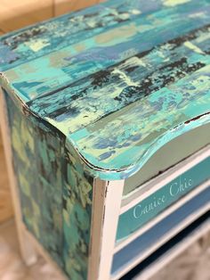 an old dresser has been painted with blue and green paint on the top, along with matching drawers