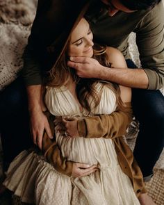 a man and woman sitting on top of each other in front of a bed together