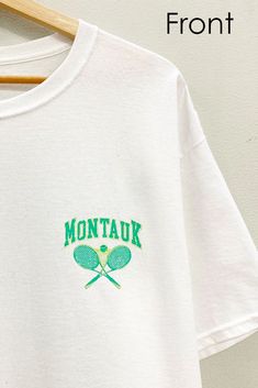 Elevate your court style with our Montauk Tennis Club Short Sleeve Tee. Crafted for comfort and performance, this oversized graphic tee features bold "MONTAUK TENNIS-NEW YORK" branding on both the front and back. Serve up a winning look both on and off the court with this iconic piece. White Graphic Tennis T-shirt, White Screen Print Sports Top, Sporty White Graphic Print Tops, White Screen Print Tops For Sports, Sporty Tennis Tops For Sports Season, Sporty Screen Print T-shirt For Tennis, Green Logo Print Athleisure T-shirt, Green Athleisure T-shirt With Logo Print, Sporty White Tops With Front Print