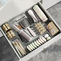 an open drawer with various items in it on top of a counter next to a sink