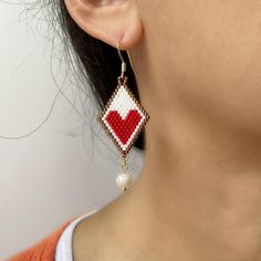 These Red Heart Drop Earrings are the perfect birthday gift for a sister who appreciates unique handmade jewelry. Adorned with lustrous freshwater pearls and a diamond shape with small red heart.these exquisite handwoven earrings are sure to make a statement. The intricate brick stitch design adds a touch of elegance to these one-of-a-kind earrings. Treat your sister to a truly special and thoughtful gift with these beautiful Heart Drop Earrings. Closure: hook Length: 2.56 inches Width: 0.8 inches Quantity:1 pair Handmade Heart Earrings For Valentine's Day Gift, Heart Beads Dangle Earrings For Gift, Gift Heart Beads Drop Earrings, Handmade Dangle Heart Earrings For Gift, Beaded Dangle Heart Earrings For Gift, Beaded Heart Drop Earrings As Gift, Heart Beads Drop Earrings For Gift, Beaded Heart Drop Earrings For Gifts, White Heart Earrings With Ear Wire As A Gift