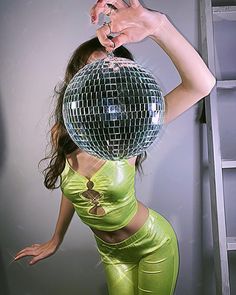 a woman in green is holding a disco ball