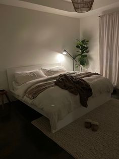 a bedroom with a bed, lamp and rug on the floor in front of a window