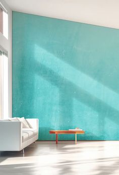 an empty room with a couch and table in front of a green wall that is painted white