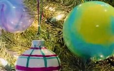 three ornaments hanging from a christmas tree in front of a blue and green ornament