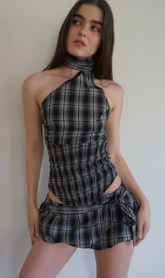 a woman wearing a black and white checkered dress with a high neck tie around her waist