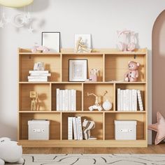 a wooden book shelf filled with lots of books next to a pink wall mounted teddy bear