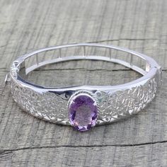 Regal and beautiful, an amethyst orchid blooms in an argent jungle. Silver vines surround the sparkling gem in this bracelet by Hema. .925 Sterling silver Silver Amethyst Bangle Bracelet, Silver Amethyst Bangle Bracelets, Silver Amethyst Gemstone Bangle, Amethyst Bangle Bracelets For Anniversary, Elegant Amethyst Bangle Bracelet, Elegant Silver Amethyst Bangle, Purple Amethyst Bangle, Silver Oval Amethyst Bracelets, Blue Topaz Pendant Necklace