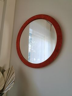 a round mirror hanging on the wall next to a vase