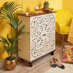 a white cabinet sitting next to a potted plant