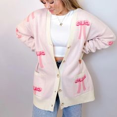 Stay Cozy And Chic With Our Oversized Bow Cardigan. Crafted From Soft, Luxurious Knit Fabric, This Cardigan Features An Effortlessly Elegant Bow Design Throughout , Adding A Touch Of Femininity To Your Look. With Its Relaxed Fit And Versatile Style, It's Perfect For Layering Over Your Favorite Tops For A Polished Yet Comfortable Ensemble. Whether You're Lounging At Home Or Stepping Out For A Casual Outing, This Cardigan Is Sure To Keep You Stylishly Snug All Day Long. Features - Front Buttons - Pink V-neck Cardigan For Loungewear, Chic Pink V-neck Cardigan, Trendy Pink V-neck Outerwear, Cute Winter Loungewear Cardigan, Oversized Pink Sweater For Winter, Cozy Pink V-neck Outerwear, Feminine Cream Cardigan For Winter, Pink Cardigan For Fall Loungewear, Feminine Long Sleeve Sweater For Day Out