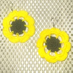 two yellow and black crochet flower earrings on a gray tablecloth with checkered cloth