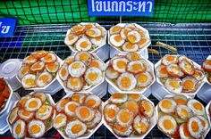 there are many trays of food on display at this market place, including eggs and other foods