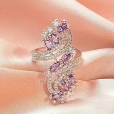 This stunning asymmetrical ring from Barbie Brides is the perfect gift for any occasion. The pear-shaped, lab-created amethyst stone shines beautifully in the white gold-plated copper setting, surrounded by excellent cut-grade cubic zirconia stones. The ring is nickel-free and features a bohemian-inspired design, making it both beautiful and comfortable to wear. Whether you're looking for an engagement ring, a Mother's Day gift, or a special Valentine's Day surprise, this luxury amethyst ring is sure to impress. Its purple and silver color scheme is both elegant and eye-catching, while its unique features make it a one-of-a-kind piece of fashion jewelry. Amethyst Ring Engagement, Zircon Ring, Watches Women Fashion, Color Ring, Mua Sắm, Valentin Nap, Types Of Rings, San Valentino, Jewelry Trends