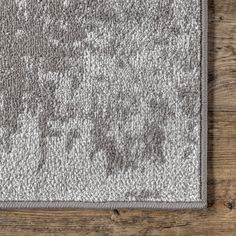 a gray rug on top of a wooden floor with white and grey designs in the middle