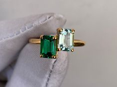 an emerald and diamond ring is being held by a glove