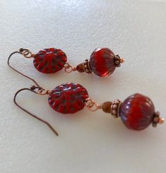 two red earrings are sitting on a white surface