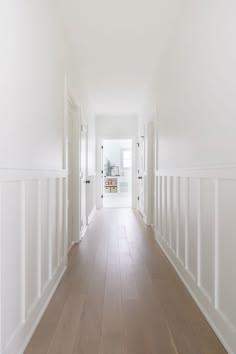 an empty hallway with white walls and wood floors