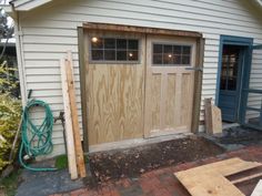 two garage doors are being installed on the side of a house in front of a blue door