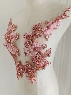 the back of a dress with pink beading and sequins is shown on a mannequin