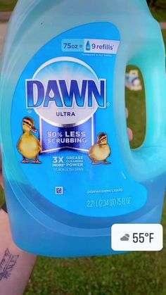 a person holding up a bottle of dawn ultra laundry deterant on the grass in front of them