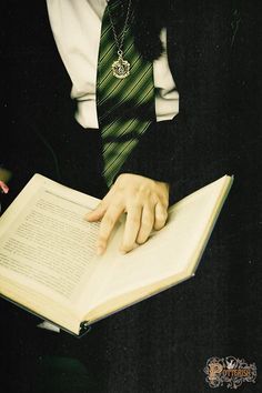 a man wearing a suit and tie holding an open book with both hands on it