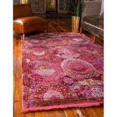 a large pink rug in a living room with a leather chair and potted plant