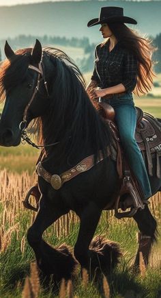 a woman riding on the back of a black horse in a field with tall grass