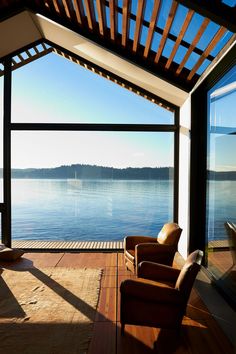 an open room with chairs and a view of the water from it's deck