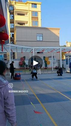 people are walking down the street in front of some stores and buildings with red lanterns