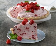 two pies with raspberries on them sitting on plates