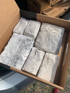 a box full of white marble blocks sitting on the ground next to a red fire hydrant