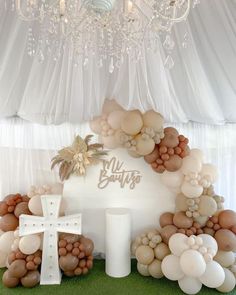 a table topped with balloons and a white cross on top of it next to a chandelier