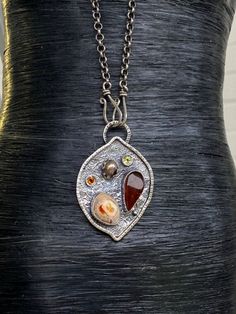 "Artisan Amber with Mexican Fire Opal pendant in sterling silver Hand-made Sterling Silver 925 Stones used: Baltic Amber, Mexican Fire Opal Purple Pearl, Peridot, Citrine Height - 2\", Width - 1 3/8\" Unique Handcrafted One-of a-kind Design Pendant Each Piece of Jewelry in my Collection is Absolutely One of a Kind! When you start wearing a piece of my jewelry you will fall in love with it more and more each day and feel that good Energy and Love that I pass into it while creating this piece of A Unique Hand Forged Sterling Silver Necklace, Fusion Style Sterling Silver Jewelry With Stones, Silver Carnelian Pendant Necklace, Silver Freeform Sterling Silver Necklace, Freeform Sterling Silver Necklace In Silver, Sterling Silver Amber Teardrop Pendant Necklace, Amber Teardrop Pendant Necklace In Sterling Silver, Unique Sterling Silver Teardrop Pendant Necklaces, Sterling Silver Teardrop Pendant Necklace With Stones