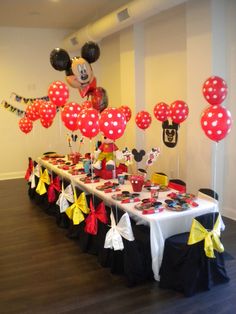 the table is set up with mickey mouse balloons and cupcakes for an event