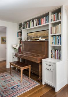 there is a piano in the corner of this room with bookshelves and a bench