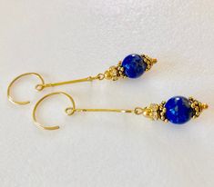 "Rich Blue lapis lazuli gemstones dangle from 18k gold vermeil Art Deco wands with antique gold bead cap and rhinestone accents. Beautiful 10mm high quality lapis lazuli gems are wire wrapped onto 18k gold vermeil over .925 Sterling silver Art Deco connectors accented with Czech glass rhinestones and antique gold pewter bead caps by Tierracast. Made in USA. Earrings hang from handmade 24k gold vermeil open hoops. Total drop is 2 3/8\"." Gold Lapis Lazuli Pierced Earrings, Blue Drop Earrings, Gold Plated, Gold Lapis Lazuli Gemstone Earrings, Blue Gemstone Gold Plated Earrings, Gold Pierced Earrings With Lapis Lazuli, Elegant Lapis Lazuli Gemstone Earrings, Blue Nickel-free Linear Earrings For Gift, Blue Gold Plated Drop Earrings, Blue Gold-plated Drop Earrings