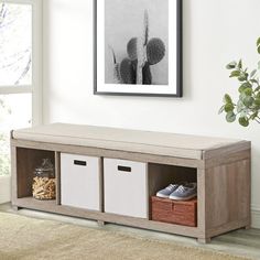 a large wooden bench with baskets underneath it in a living room area next to a potted plant