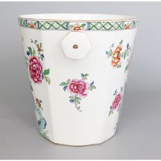 a white bucket with flowers painted on the side and gold trimming around the rim