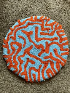 an orange and blue circular rug on the ground