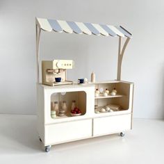 a toy kitchen with an awning over it's top and shelves below the counter