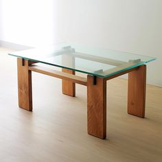 a glass table sitting on top of a hard wood floor next to a white wall