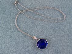 "This faceted dark blue sapphire is set in a round floral designed bezel frame. A fan shaped bail holds this deep blue gem on an oxidized silver cable link chain, closed with a lobster claw clasp. The 18mm (3/4\") Czech glass gem is dark blue and has many facets that reflect the light. The chain in 20\" in length. Chain length can be ordered from 16\" up to a 24\" with no additional cost. Just message me with your request at time of purchase. This lovely sparkling cobalt blue necklace would enha Blue Faceted Jewelry For Formal Occasions, Victorian Style Blue Round Pendant Jewelry, Victorian Round Faceted Jewelry, Victorian Faceted Round Jewelry, Round Sapphire Cabochon Necklaces, Antique Blue Sapphire Jewelry, Round Sapphire Cabochon Necklace, Blue Round Cabochon Jewelry, Victorian Blue Gemstone Necklace