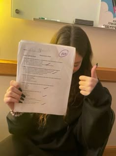 a woman sitting in a chair holding up a piece of paper with writing on it