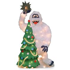 a christmas tree with lights on it and a monster holding a star in its hand