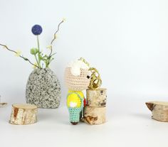 small crocheted figurines sitting next to wooden logs and flowers