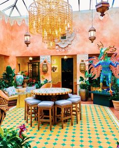 a room filled with lots of tables and chairs under a chandelier above them